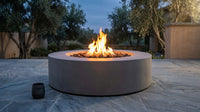 Brookhurst 43 In. W X 13 In. H round Outdoor GFRC Liquid Propane Fire Pit Table in Flint with Lava Rocks — Lifestyle